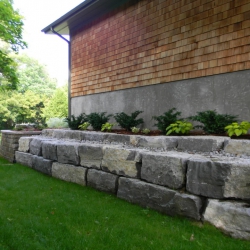 Limestone retaining wall along side of house