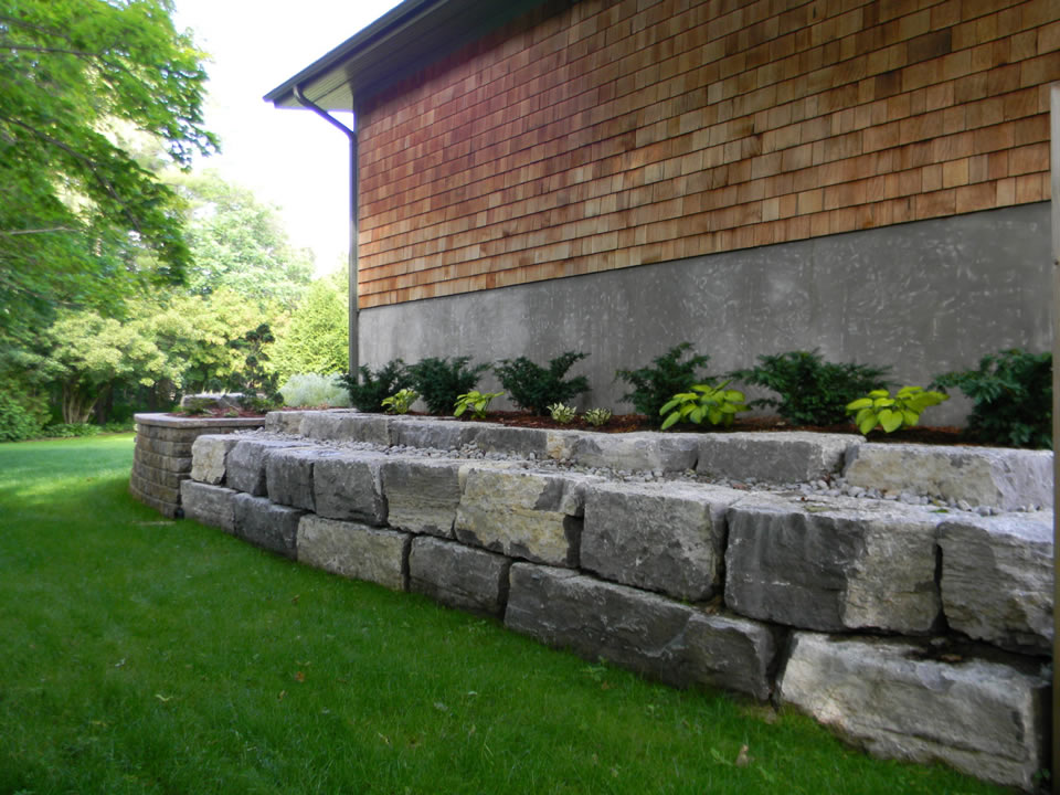 Limestone retaining wall along side of house